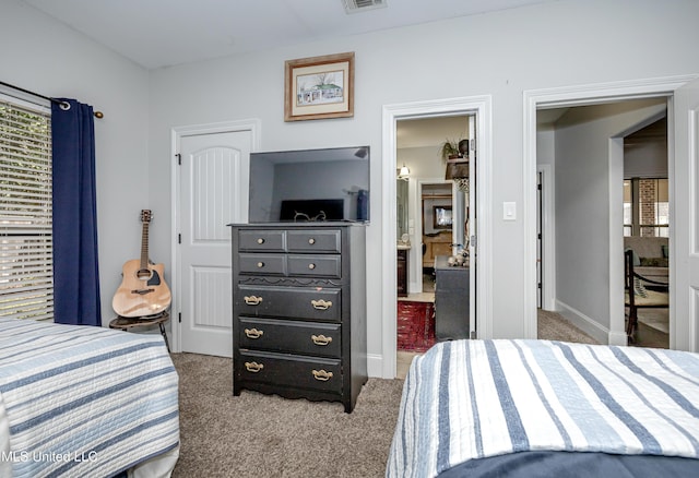 carpeted bedroom featuring baseboards, visible vents, and connected bathroom