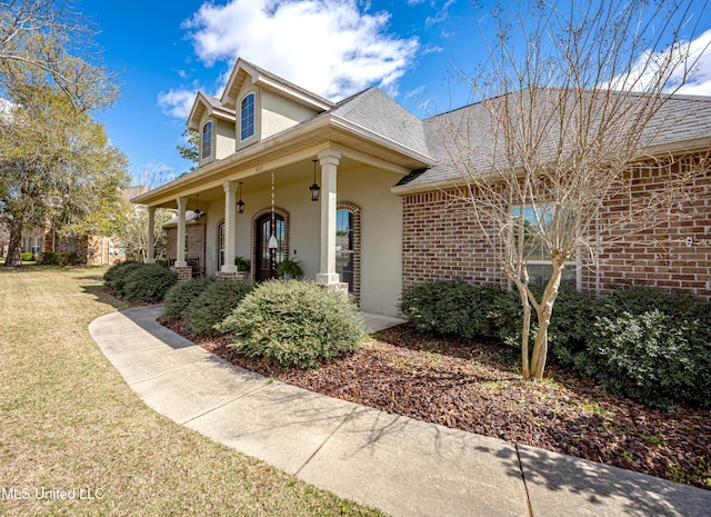 exterior space featuring stucco siding, brick siding, and a front lawn