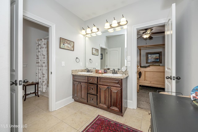 full bathroom featuring a sink, baseboards, double vanity, and tile patterned floors