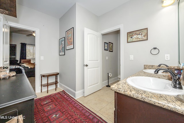 bathroom featuring a sink, ensuite bath, tile patterned flooring, double vanity, and baseboards