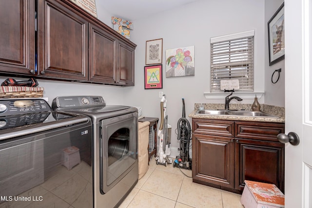 laundry room featuring cabinet space, light tile patterned floors, washer and dryer, and a sink