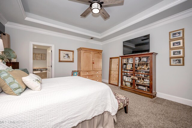 carpeted bedroom with crown molding, ceiling fan, baseboards, a tray ceiling, and ensuite bathroom