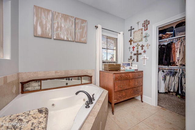 full bath with tile patterned flooring, a tub with jets, vanity, and a walk in closet