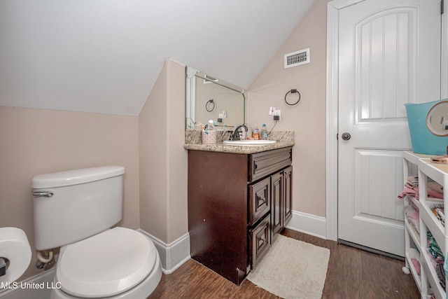 bathroom with visible vents, toilet, wood finished floors, lofted ceiling, and vanity