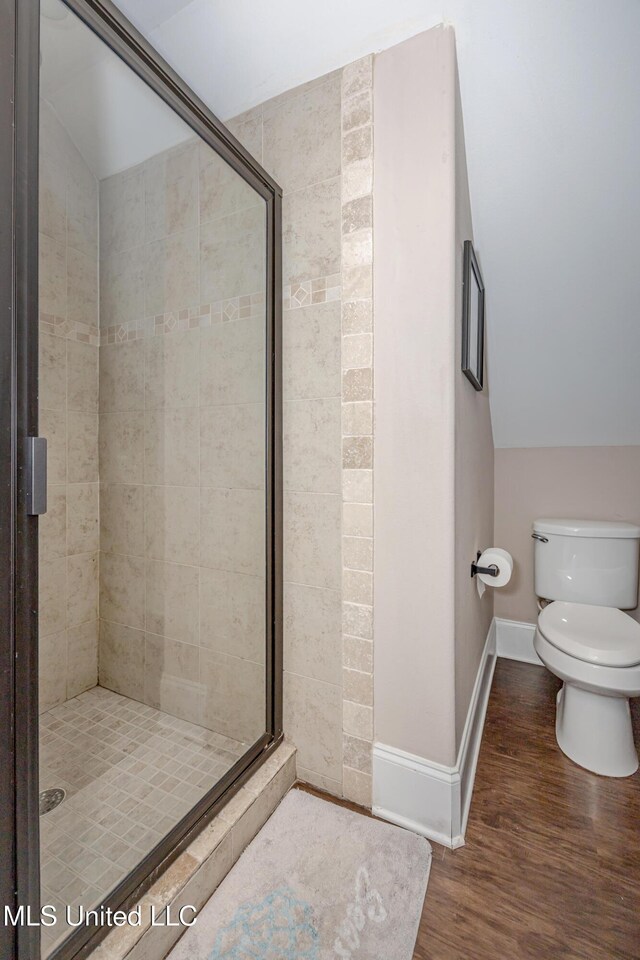 full bathroom with toilet, wood finished floors, a stall shower, and baseboards