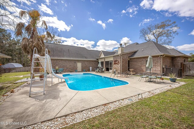 view of swimming pool with a fenced in pool, a water slide, fence, a yard, and a patio