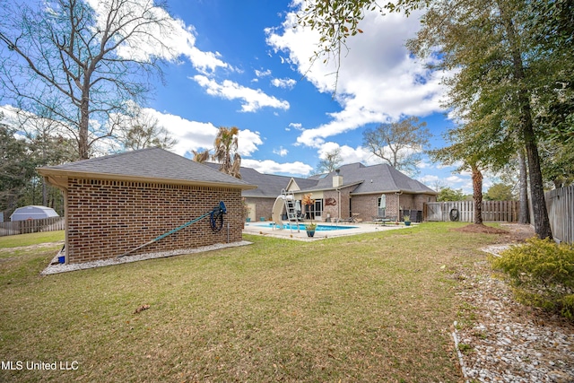 back of house featuring a fenced backyard, a yard, a fenced in pool, brick siding, and a patio area