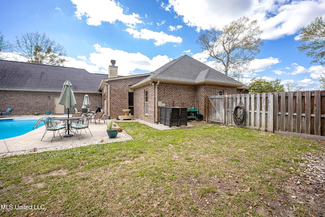 back of property featuring fence, roof with shingles, a lawn, a patio area, and brick siding