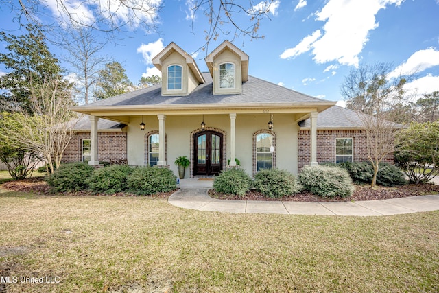 view of front of property with stucco siding, a front lawn, french doors, a shingled roof, and brick siding