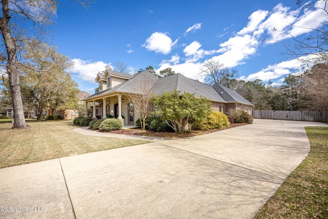 view of side of property with concrete driveway, a lawn, and fence