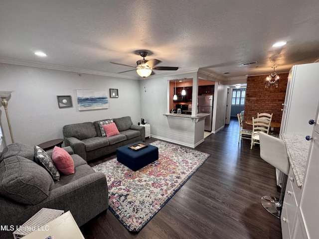 living room featuring brick wall, dark hardwood / wood-style floors, crown molding, a textured ceiling, and ceiling fan with notable chandelier