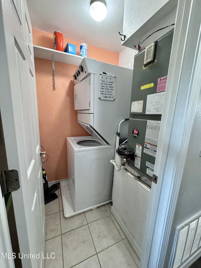 laundry room with light tile patterned floors and stacked washing maching and dryer