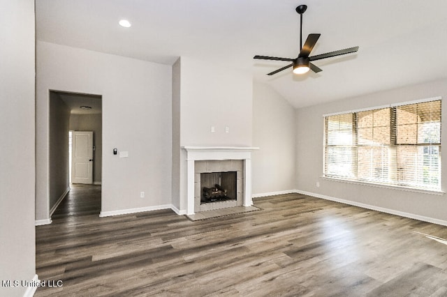 unfurnished living room with dark hardwood / wood-style floors, vaulted ceiling, ceiling fan, and a tiled fireplace