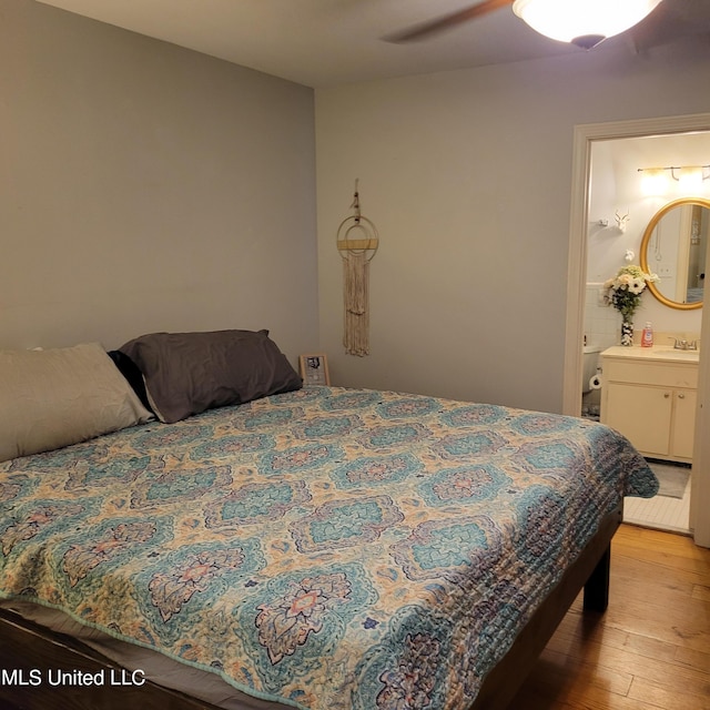 bedroom with ceiling fan, light wood-style flooring, ensuite bathroom, and a sink