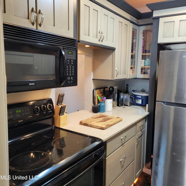 kitchen with glass insert cabinets, black appliances, and light countertops