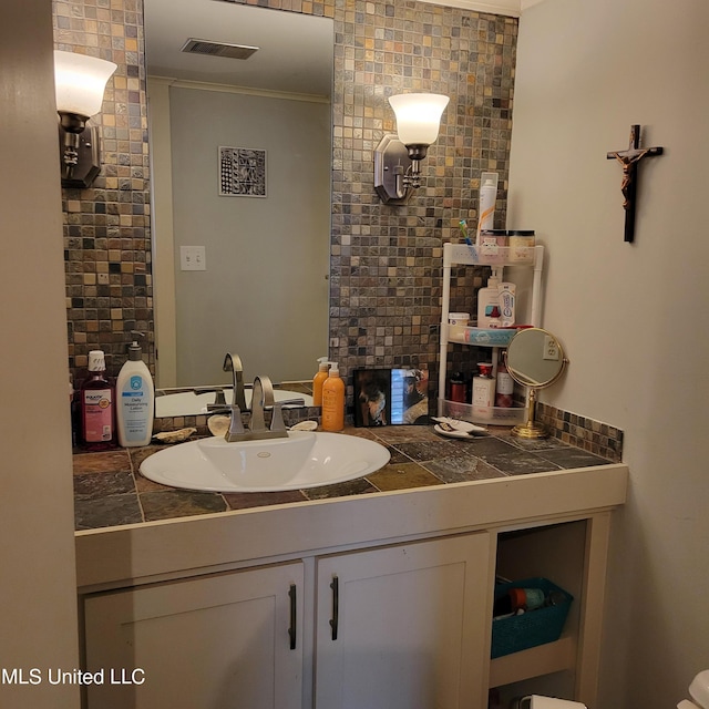 bathroom featuring visible vents, ornamental molding, and vanity