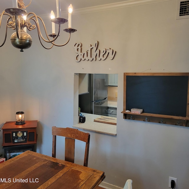 dining area featuring crown molding, a notable chandelier, and visible vents