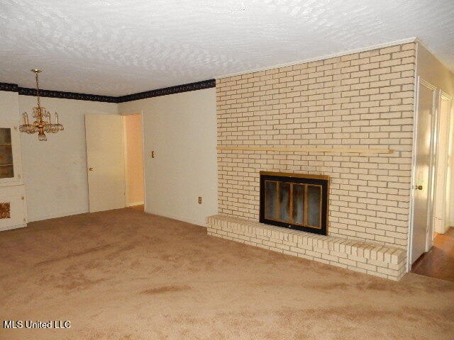 unfurnished living room with carpet, a textured ceiling, and an inviting chandelier