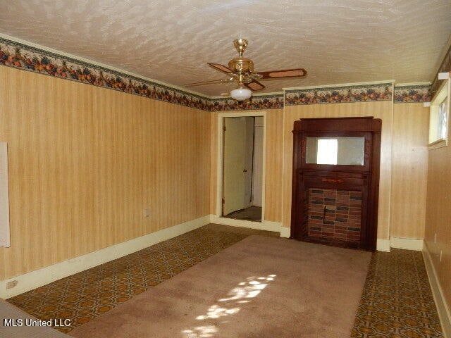 carpeted spare room featuring ceiling fan and a textured ceiling