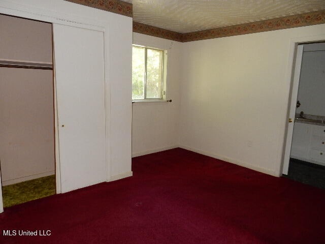 unfurnished bedroom with a closet and dark colored carpet