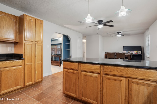 kitchen with ceiling fan, tile patterned floors, a textured ceiling, and pendant lighting