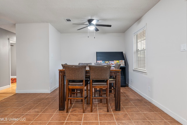 dining room with tile patterned flooring, a textured ceiling, and ceiling fan