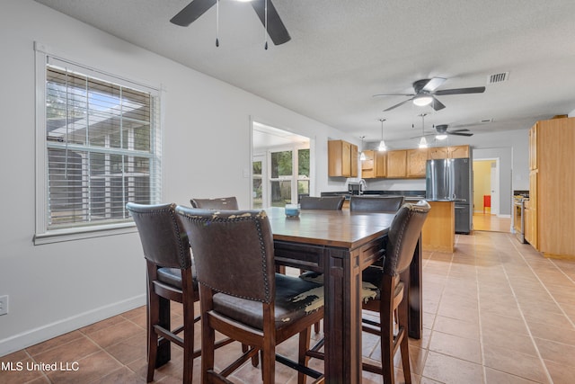 tiled dining space with ceiling fan, a textured ceiling, and sink