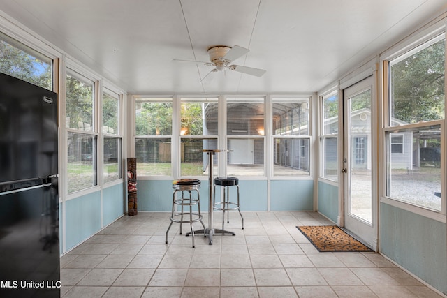 unfurnished sunroom featuring ceiling fan and plenty of natural light