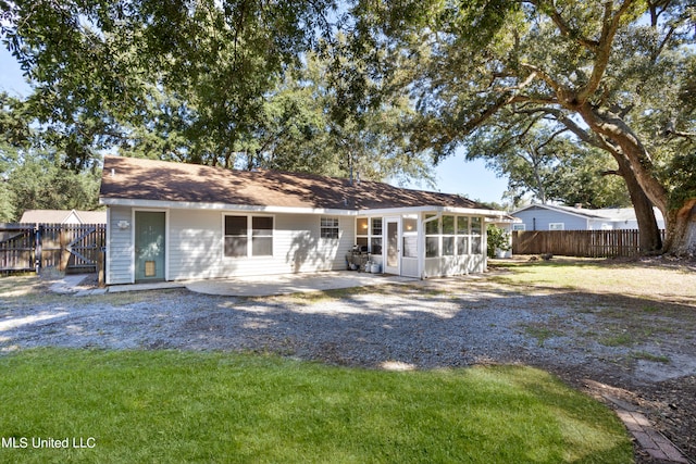 rear view of house with a patio, a lawn, and a sunroom