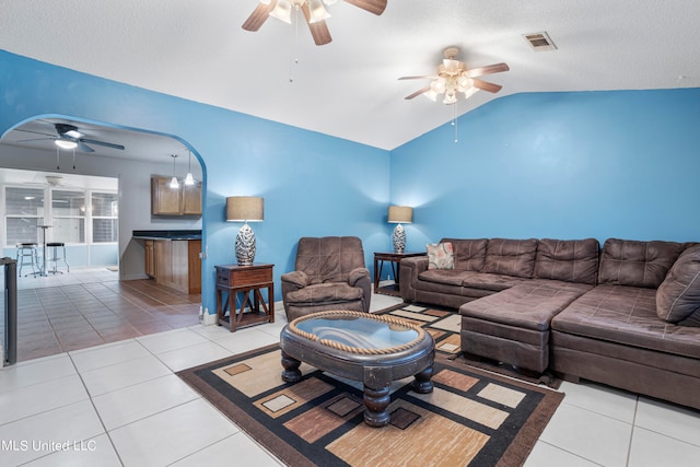 tiled living room featuring vaulted ceiling, a textured ceiling, and ceiling fan