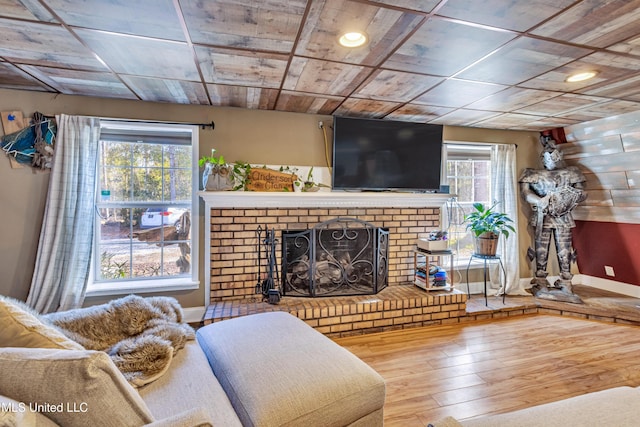 living room featuring a brick fireplace, plenty of natural light, hardwood / wood-style floors, and wooden ceiling