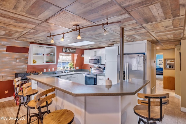 kitchen with a kitchen breakfast bar, white cabinetry, kitchen peninsula, and stainless steel appliances