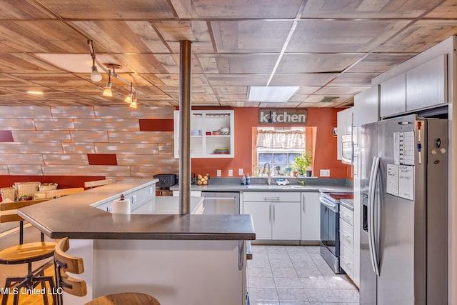 kitchen with appliances with stainless steel finishes, white cabinetry, sink, wooden ceiling, and a breakfast bar area