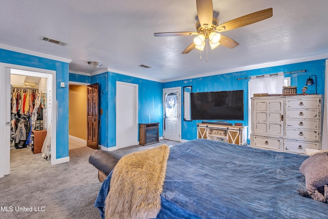 bedroom featuring ceiling fan, carpet, crown molding, a walk in closet, and a closet