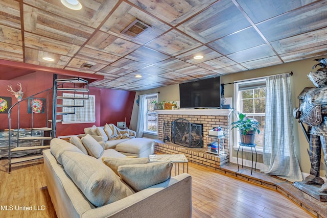 living room with a healthy amount of sunlight, wood-type flooring, a fireplace, and coffered ceiling