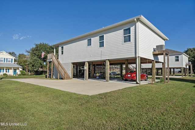 back of house featuring central AC, a yard, and a carport