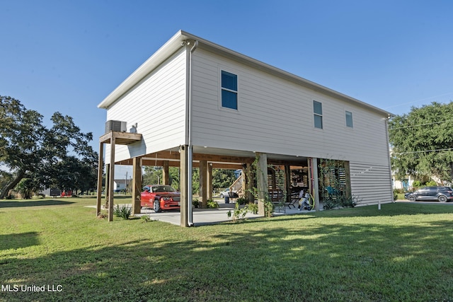 back of property with a yard, a patio, and a carport