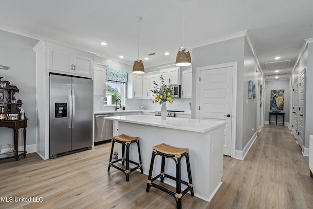 kitchen featuring stainless steel appliances, light hardwood / wood-style flooring, a kitchen island, and white cabinets