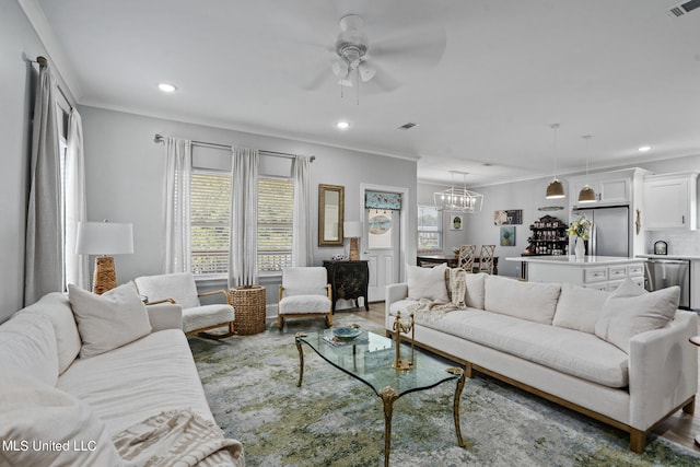 living room featuring crown molding, a healthy amount of sunlight, wood-type flooring, and ceiling fan with notable chandelier