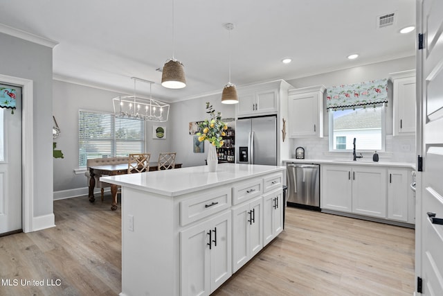 kitchen with white cabinets, stainless steel appliances, plenty of natural light, and pendant lighting