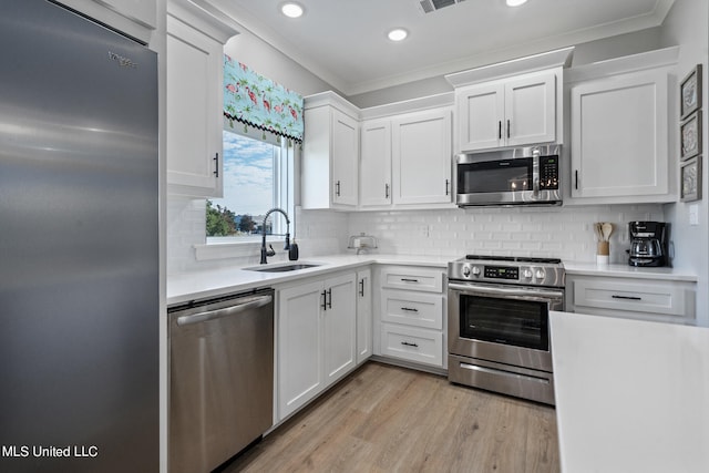 kitchen featuring crown molding, stainless steel appliances, sink, and white cabinets