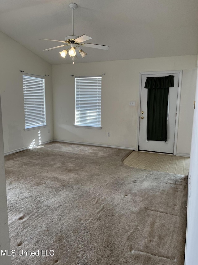 carpeted spare room featuring ceiling fan and vaulted ceiling