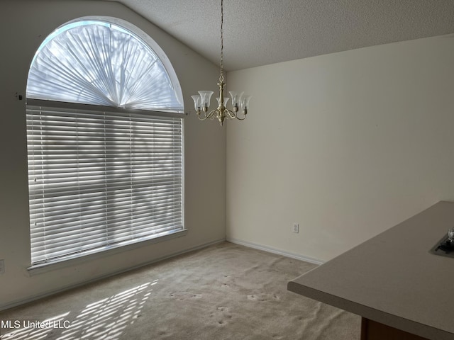 unfurnished dining area featuring a textured ceiling, a chandelier, lofted ceiling, and carpet floors