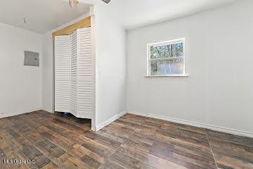 unfurnished bedroom featuring a closet, dark hardwood / wood-style flooring, and electric panel