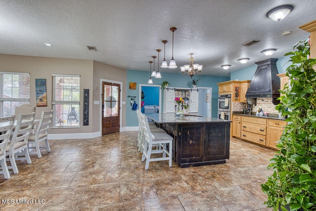 kitchen featuring tasteful backsplash, a breakfast bar area, decorative light fixtures, a chandelier, and a large island