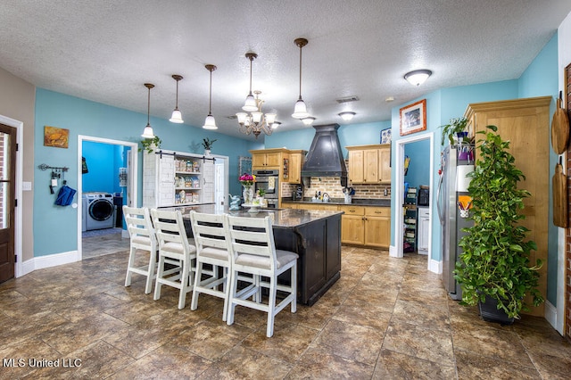 kitchen featuring a center island, decorative backsplash, a breakfast bar area, custom exhaust hood, and washer / clothes dryer