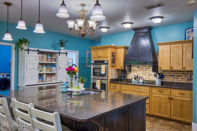 kitchen featuring stainless steel double oven, premium range hood, decorative light fixtures, a kitchen breakfast bar, and a center island