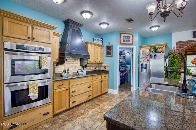 kitchen with stainless steel appliances, a textured ceiling, hanging light fixtures, sink, and custom exhaust hood