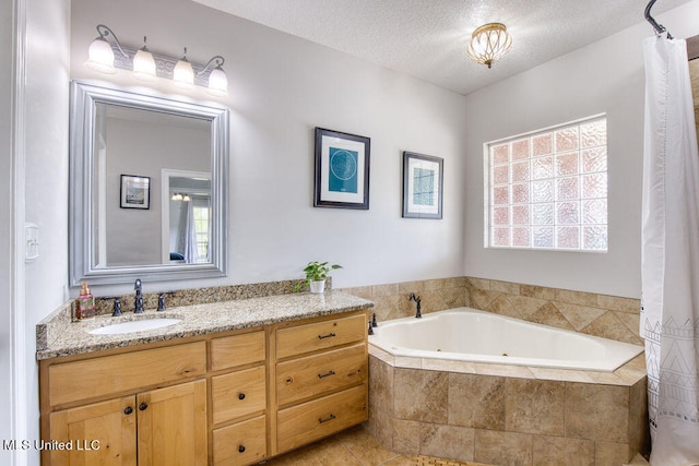 bathroom with a textured ceiling, vanity, tiled tub, and tile patterned floors