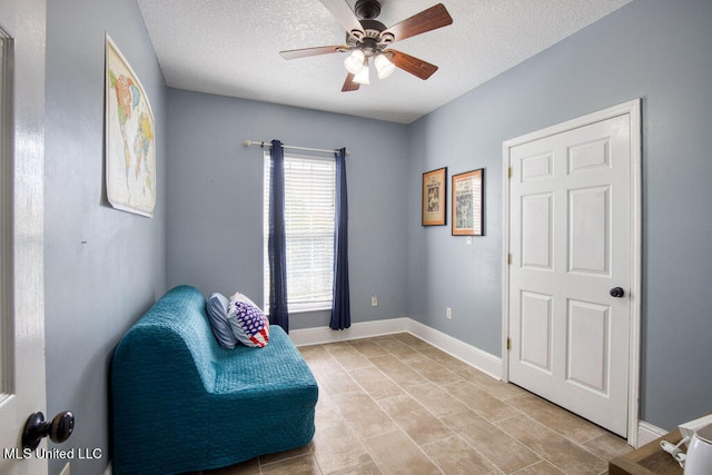 living area with a textured ceiling and ceiling fan